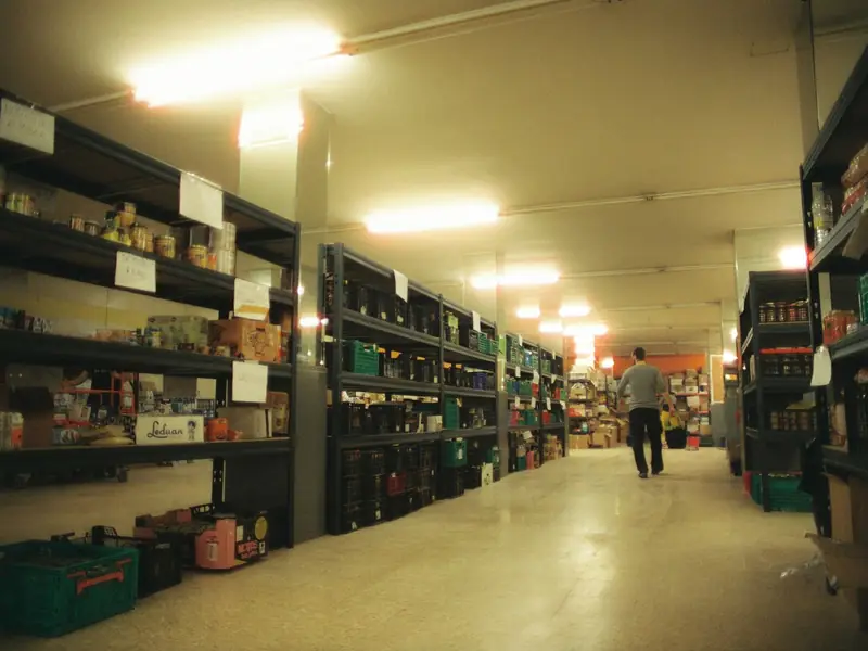 A warehouse aisle with shelving under ceiling lights